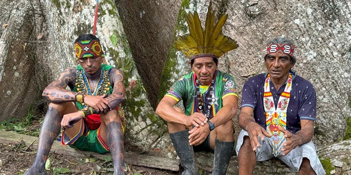 Three Indigenous men sitting beside a tree