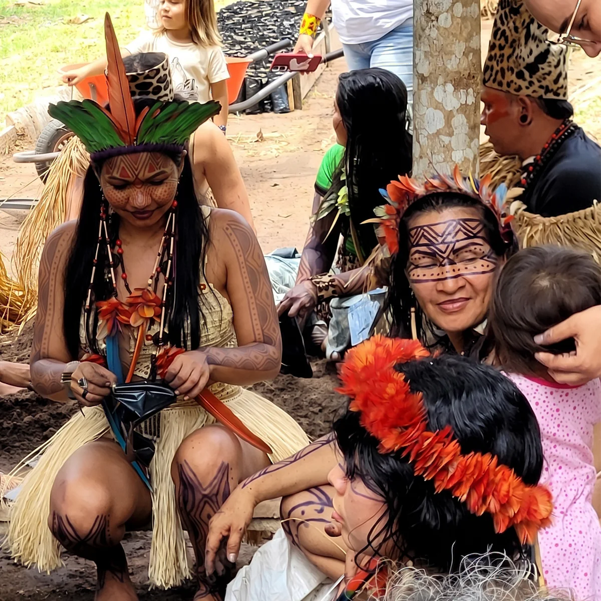 People wearing feathered headdresses and body paint gathered outdoors